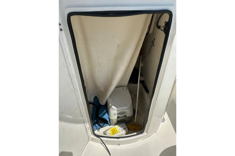 Slide: The Image of 2012 Sundance NX25 boat interior with portable toilet and cleaning supplies. - 35