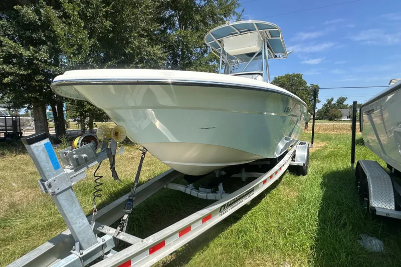 Slide: The Image of 2012 Sundance NX25 boat on trailer, parked on grass under clear sky. - 44