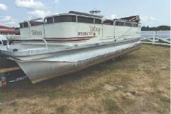 Slide: The Image of 2000 Tahoe Pontoon boat on grass, under a partly cloudy sky. - 2