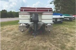 Slide: The Image of 2000 Tahoe Pontoon boat on grass, rear view with motor, trees in background. - 3