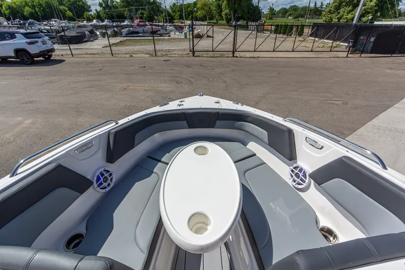 Slide: The Image of 2026 Chaparral 23 SSi boat interior with seating and table, parked near marina. - 32