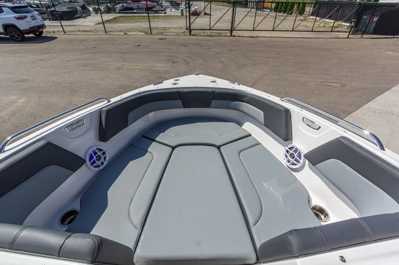 Slide: The Image of 2026 Chaparral 23 SSi boat interior with gray seating and speakers, parked outdoors. - 30