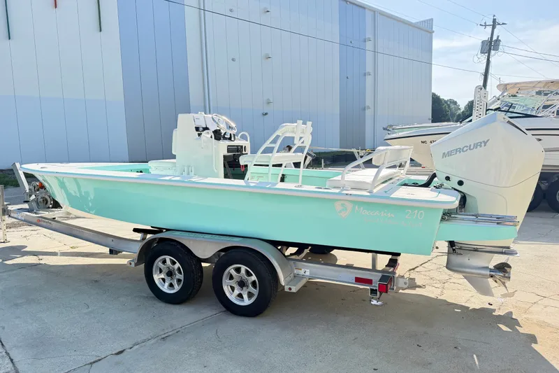Slide: The Image of 2023 Egret 21 Moccasin boat with Mercury engine on trailer, parked outdoors. - 25