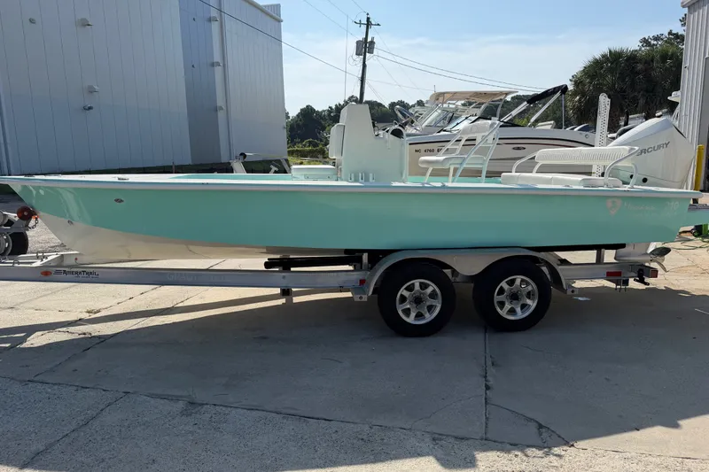 Slide: The Image of 2023 Egret 21 Moccasin boat on trailer, light blue hull, parked outdoors. - 21