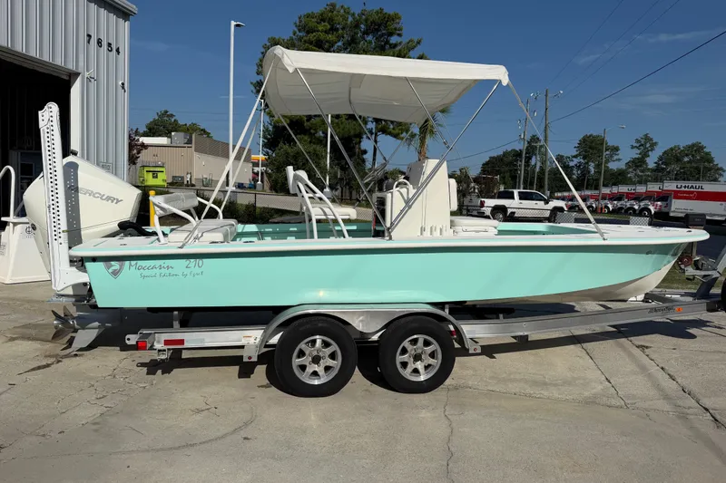 Slide: The Image of 2023 Egret 21 Moccasin boat on trailer, featuring a canopy and Mercury engine. - 46
