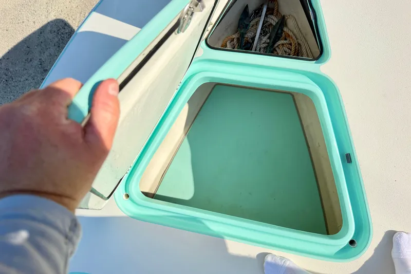 Slide: The Image of Open storage compartment on 2023 Egret 21 Moccasin boat, featuring turquoise trim and visible ropes. - 29
