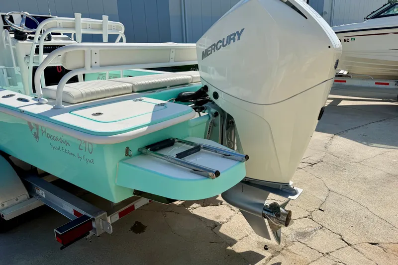 Slide: The Image of 2023 Egret 21 Moccasin boat with Mercury outboard motor, teal color, docked on trailer. - 15