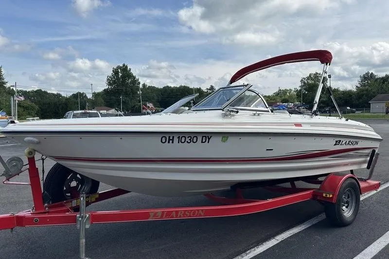 Slide: The Image of 2006 Larson 180 I/O boat on red trailer, parked outdoors under cloudy sky. - 8