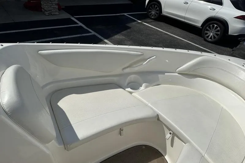 Slide: The Image of 2006 Larson 180 I/O boat interior with white seating in a parking lot. - 7