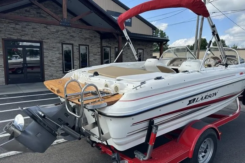 Slide: The Image of 2006 Larson 180 I/O boat on trailer, parked outside a building. - 17