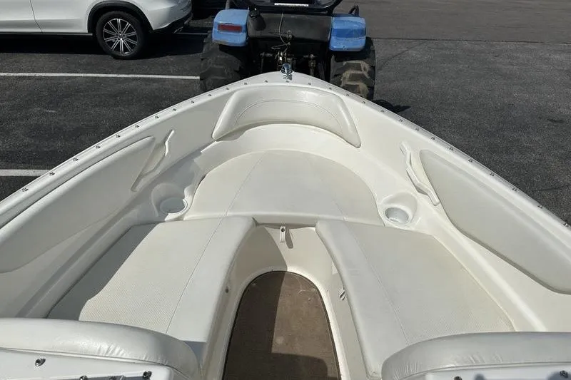 Slide: The Image of 2006 Larson 180 I/O boat interior with white seating, parked in a lot. - 14
