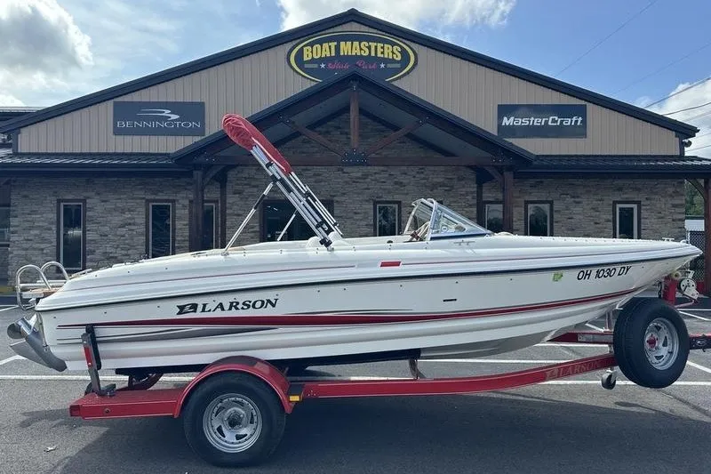 Slide: The Image of 2006 Larson 180 I/O boat on trailer outside dealership, featuring sleek white and red design. - 20