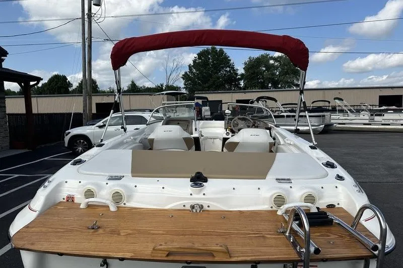 The Image of 2006 Larson 180 I/O boat with red canopy, parked outdoors under blue sky. - 1