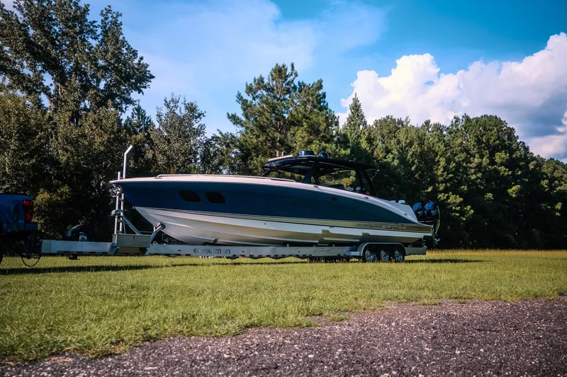Slide: The Image of 2020 Concept 44' Cuddy Cabin boat on trailer, parked on grassy area with trees. - 2