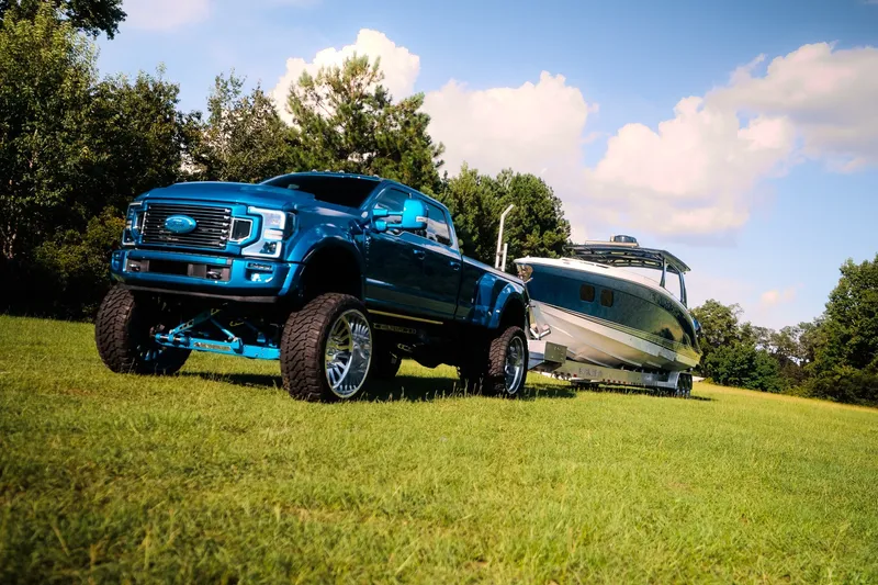 Slide: The Image of Blue truck towing a 2020 Concept 44' Cuddy Cabin boat on grassy field. - 8