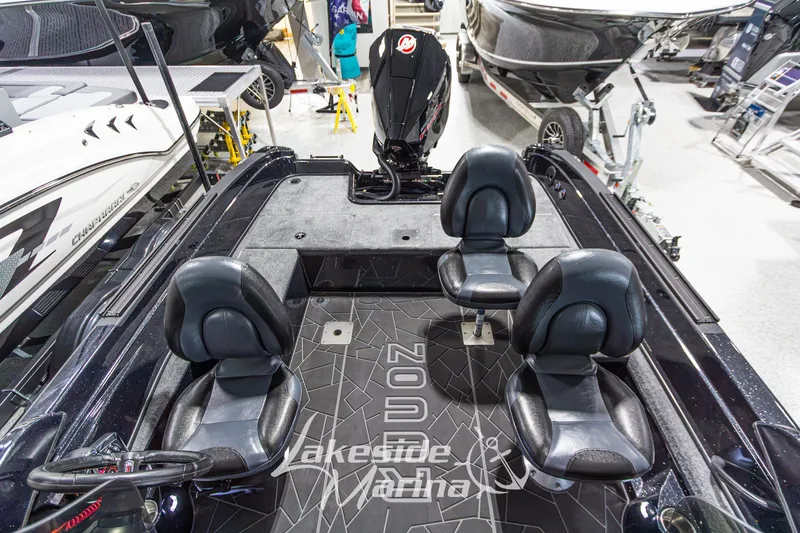 Slide: The Image of 2027 Recon 985 DC boat interior with black seating and modern design in showroom. - 18