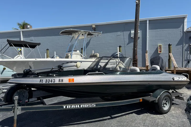 The Image of 1995 Cajun 180 boat on trailer, parked outdoors near other boats. - 1