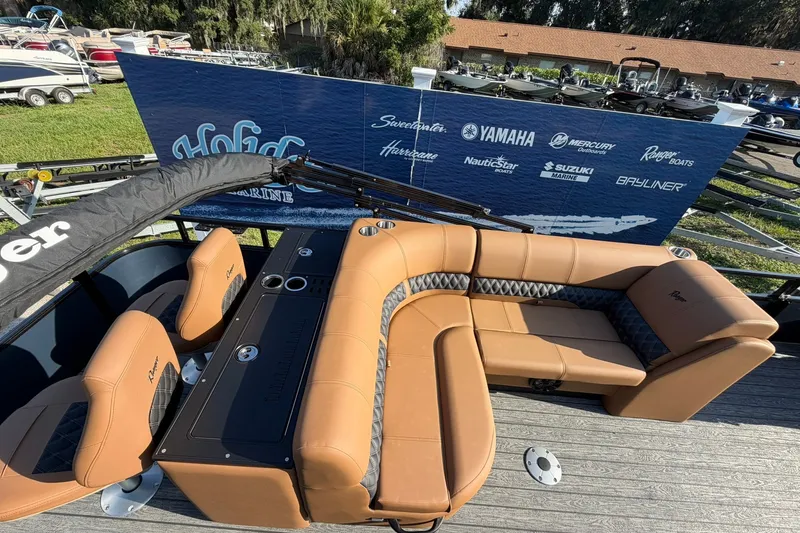 Slide: The Image of 2027 Ranger 220FC boat interior with tan seating and branded backdrop. - 17