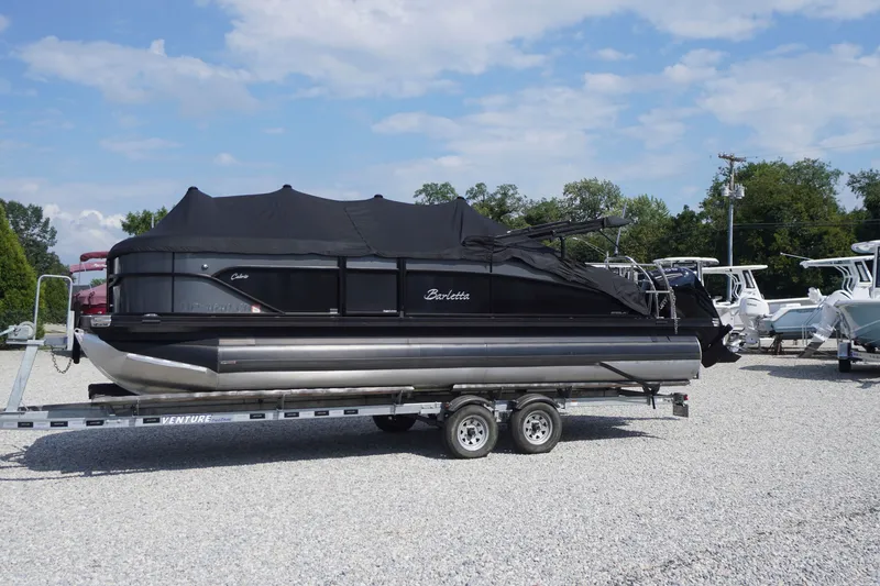 Slide: The Image of 2024 Barletta Cabrio 22UC pontoon boat on trailer, covered, in outdoor setting. - 53