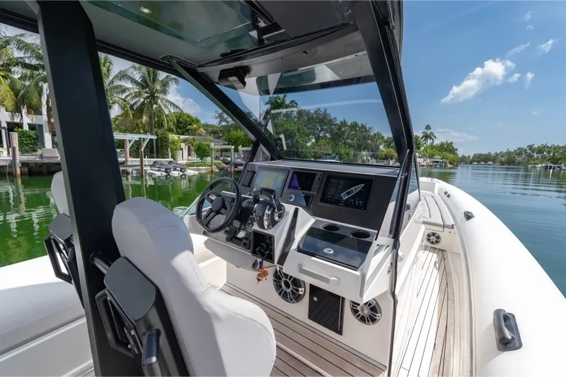 Slide: The Image of 2021 Technohull 38 Grand Sport boat interior with modern dashboard and scenic waterway view. - 31