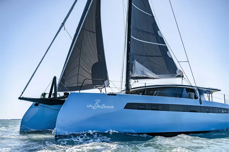 The Image of Sleek 2022 Balance 482 catamaran sailing on open water with black sails. - 0