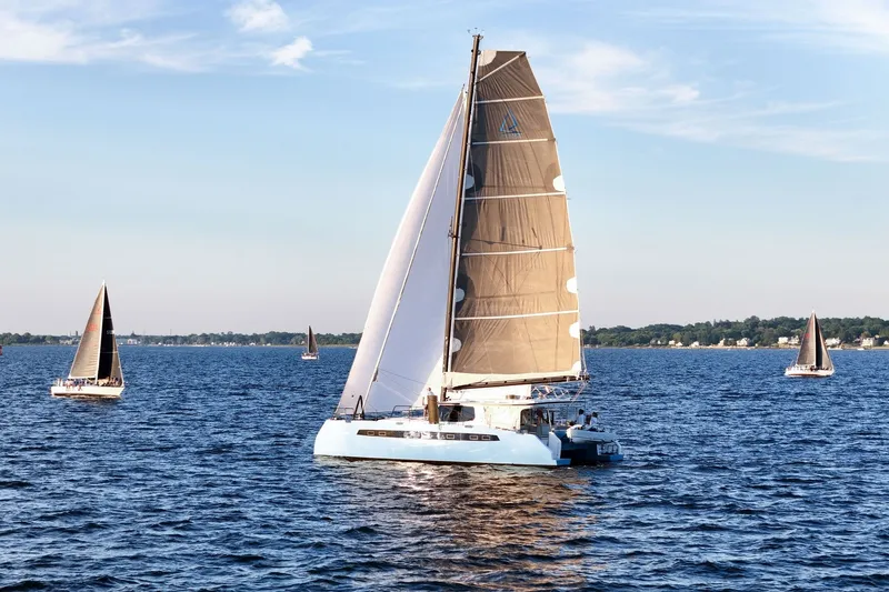 Slide: The Image of Sailboats on a serene lake, featuring a 2022 Balance 482 catamaran. - 2