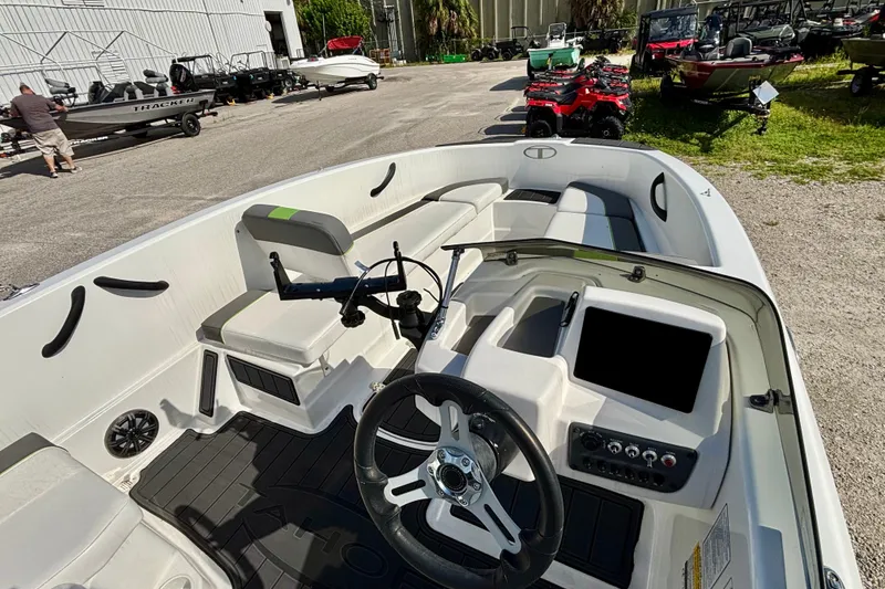 Slide: The Image of 2024 Tahoe T16 boat interior with steering wheel and seating, parked outdoors. - 10
