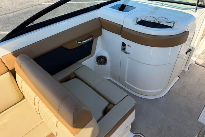 Slide: The Image of Interior of a 2015 Sea Ray 270 Sundeck boat, featuring tan seating and a compact kitchenette. - 14