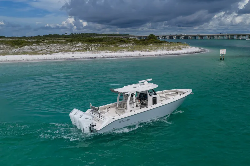 Slide: The Image of 2025 Solace 37CS boat cruising in turquoise waters near a sandy shoreline. - 22