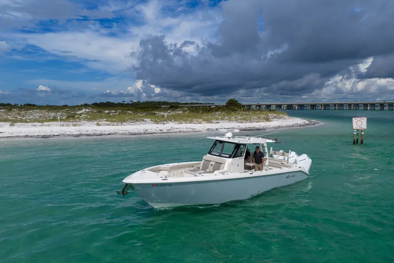 Slide: The Image of 2025 Solace 37CS boat cruising in turquoise waters near a sandy shoreline under a cloudy sky. - 24