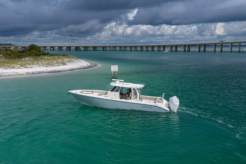 Slide: The Image of 2025 Solace 37CS boat cruising in turquoise waters near a bridge under cloudy skies. - 25
