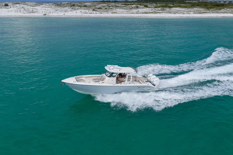 Slide: The Image of 2025 Solace 37CS boat cruising on turquoise waters near a sandy shoreline. - 15