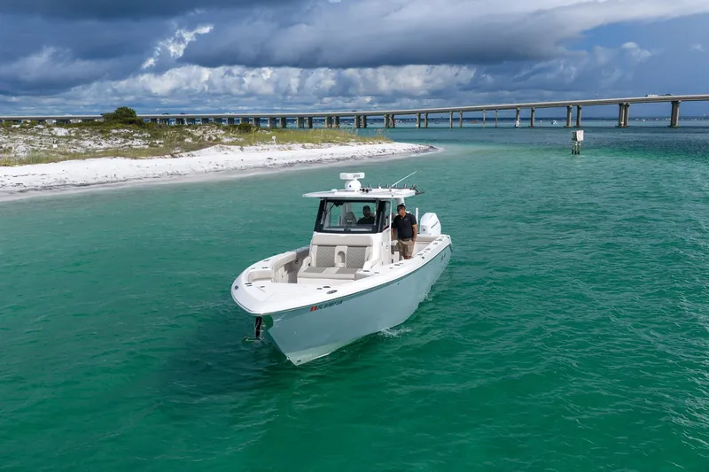 Slide: The Image of 2025 Solace 37CS boat cruising in turquoise waters near a sandy shoreline and bridge. - 30