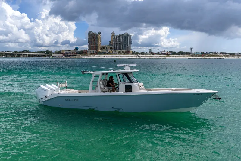 Slide: The Image of 2025 Solace 37CS boat cruising on turquoise waters near a coastal cityscape. - 28