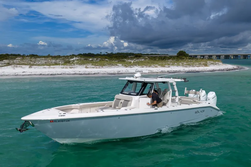 Slide: The Image of 2025 Solace 37CS boat cruising in turquoise waters near a sandy shoreline. - 21