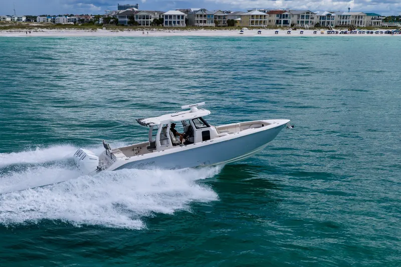 Slide: The Image of 2025 Solace 37CS boat cruising on turquoise waters near a coastal town. - 14