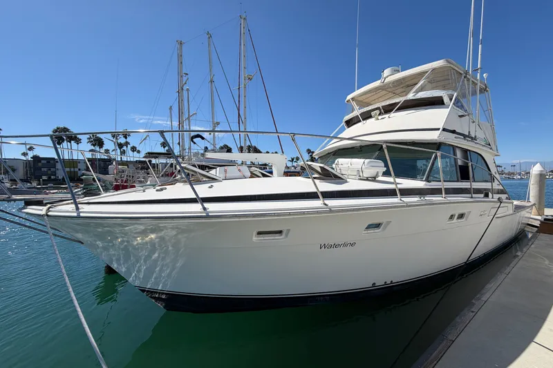 The Image of 1974 Bertram 46 Convertible yacht docked in a marina under clear blue skies. - 1