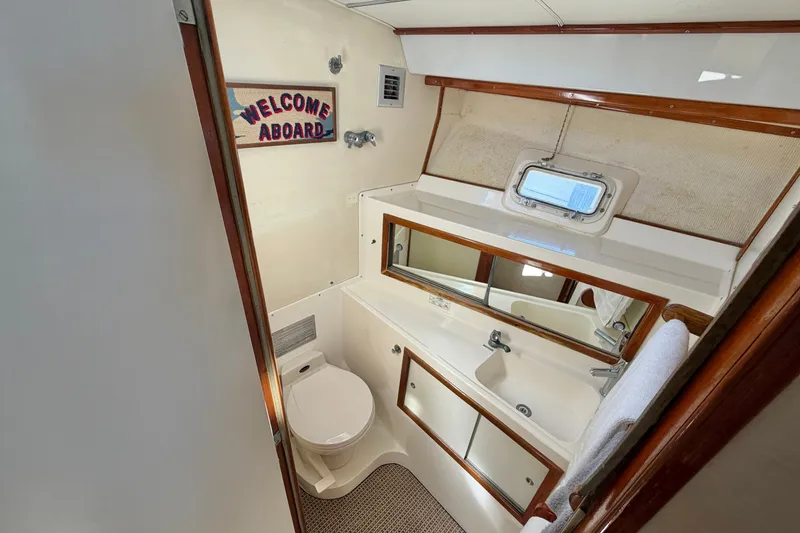 Slide: The Image of 1974 Bertram 46 Convertible yacht bathroom with mirror, sink, and "Welcome Aboard" sign. - 24