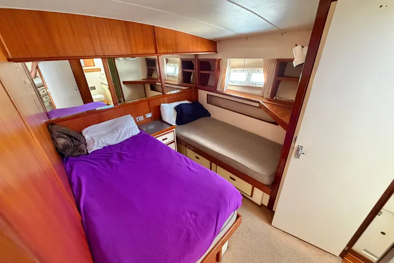 Slide: The Image of 1974 Bertram 46 Convertible yacht cabin with twin beds and wooden interior. - 23