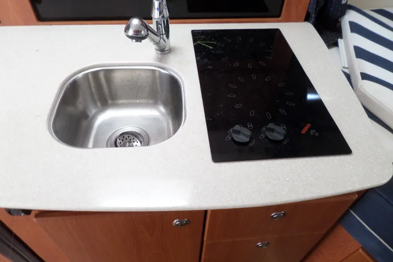 Slide: The Image of 2008 Bayliner 320 Cruiser kitchen with sink and electric cooktop. - 53