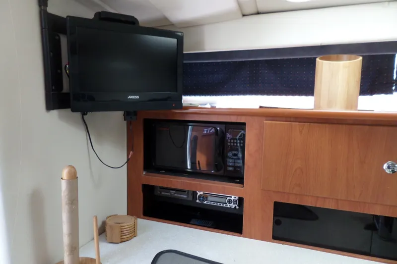 Slide: The Image of Interior of 2008 Bayliner 320 Cruiser with TV, microwave, and wooden cabinetry. - 32
