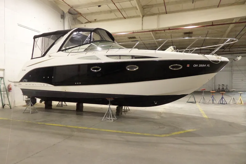 Slide: The Image of 2008 Bayliner 320 Cruiser in a warehouse, elevated on stands for maintenance. - 2