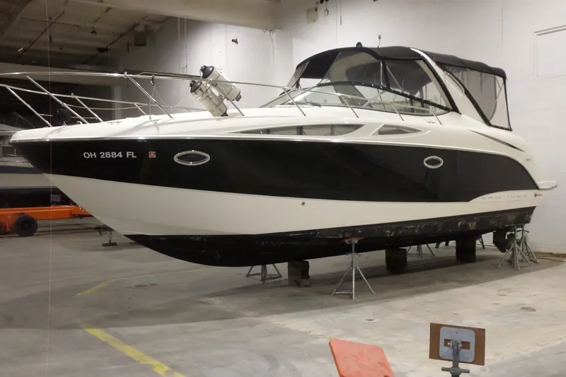 Slide: The Image of 2008 Bayliner 320 Cruiser in storage, elevated on stands, with black and white exterior. - 1