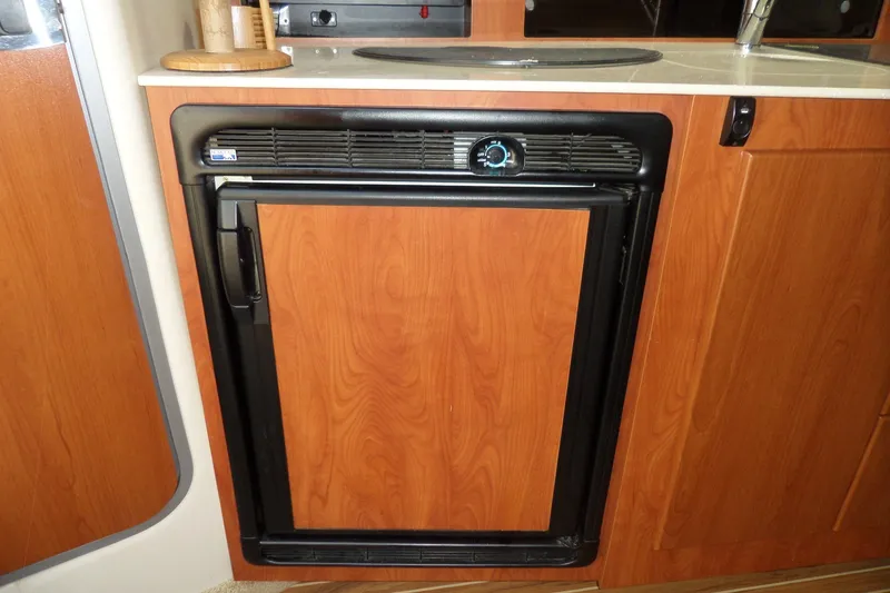 Slide: The Image of 2008 Bayliner 320 Cruiser interior with wooden cabinetry and compact refrigerator. - 31