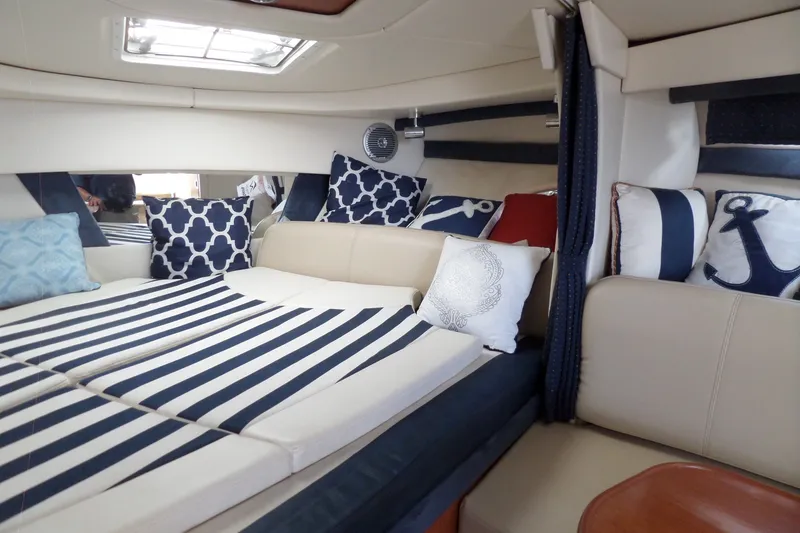 Slide: The Image of Interior of 2008 Bayliner 320 Cruiser with nautical-themed cushions and striped bedding. - 27