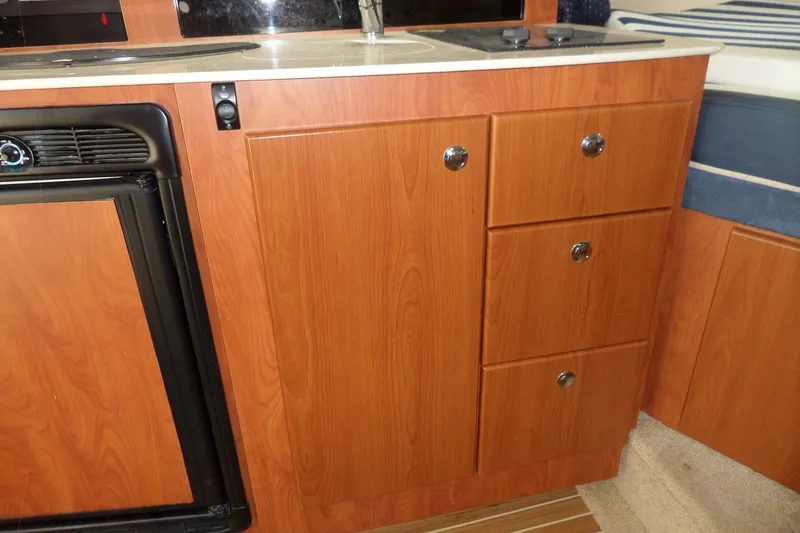 Slide: The Image of 2008 Bayliner 320 Cruiser interior kitchen with wood cabinetry and compact appliances. - 30
