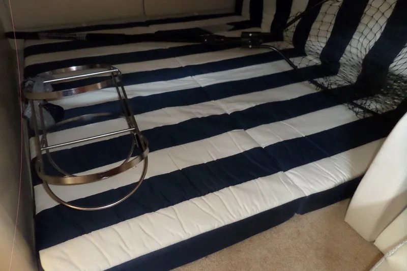 Slide: The Image of Interior of 2008 Bayliner 320 Cruiser with striped bedding and metal rack. - 46