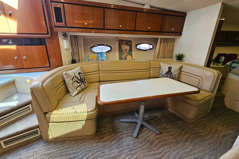 Slide: The Image of 1998 Trojan 400 Express yacht interior with beige seating, table, and nautical decor. - 31