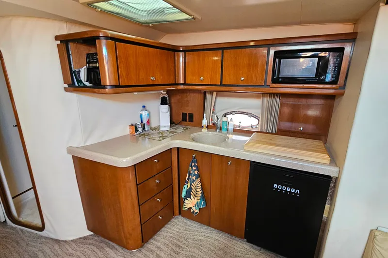 Slide: The Image of 1998 Trojan 400 Express yacht kitchen with wood cabinets, microwave, sink, and mini fridge. - 34