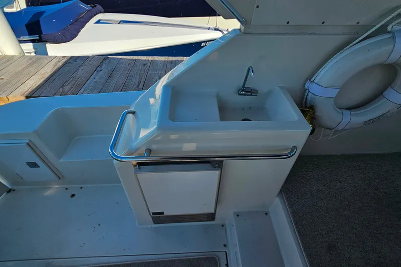 Slide: The Image of 1998 Trojan 400 Express yacht sink area with life preserver and dock view. - 14